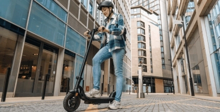 Jovem circula com trotinete eletrica Jovem com capacete circula de trotinete elétrica