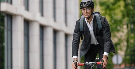 Jovem com capacete utiliza a bicicleta como meio de transporte para o trabalho.