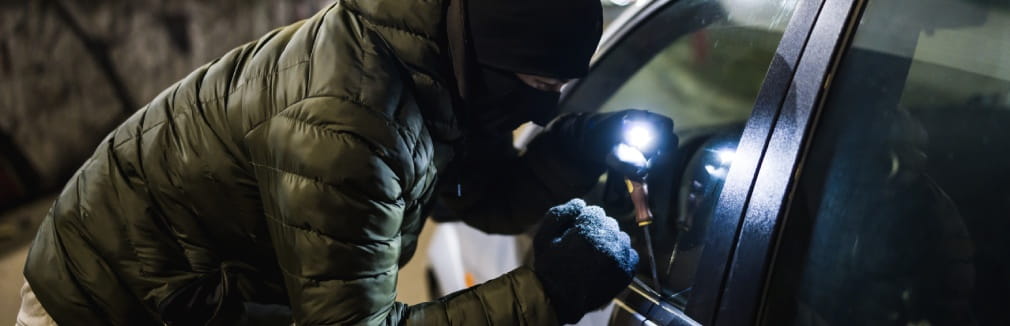 Ladrão tenta arrombar o carro com um ferro de abrir fechaduras.