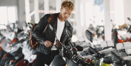 Jovem num stand de vendas à procura da moto ideal para pequenas viagens.