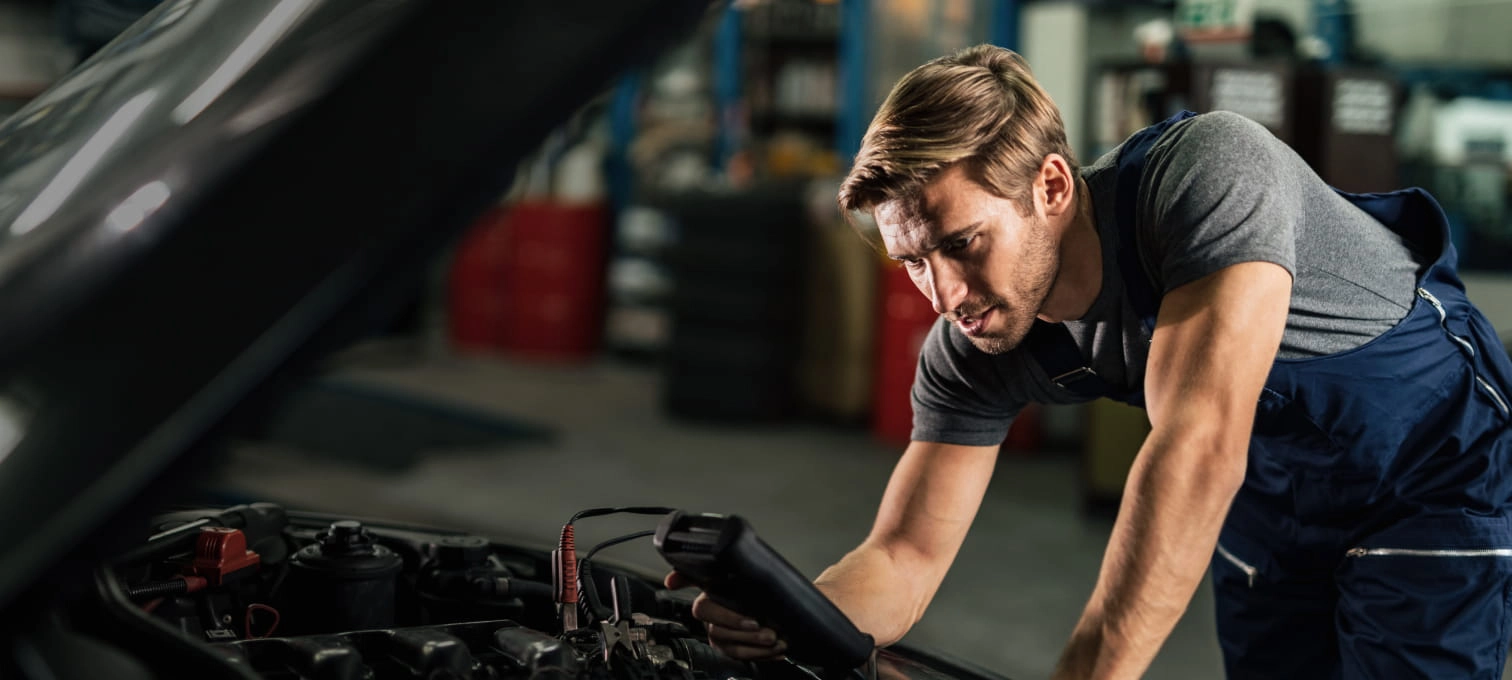 Mecânico dentro da oficina a verificar o motor de um carro