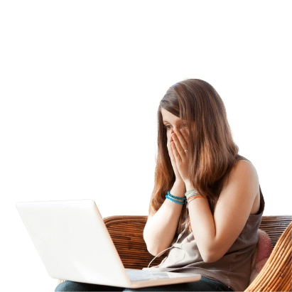 Mulher jovem sentada, com portátil sobre joelhos, a olhar para ecrã com mãos no rosto