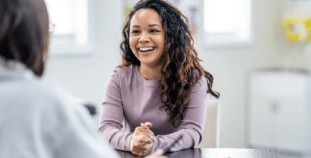 Mulher jovem a sorrir, sentada, em consulta médica
