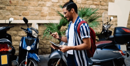 Homem jovem a pesquisar no telemóvel para comprar uma moto usada. Homem jovem a pesquisar no telemóvel para comprar uma moto usada.